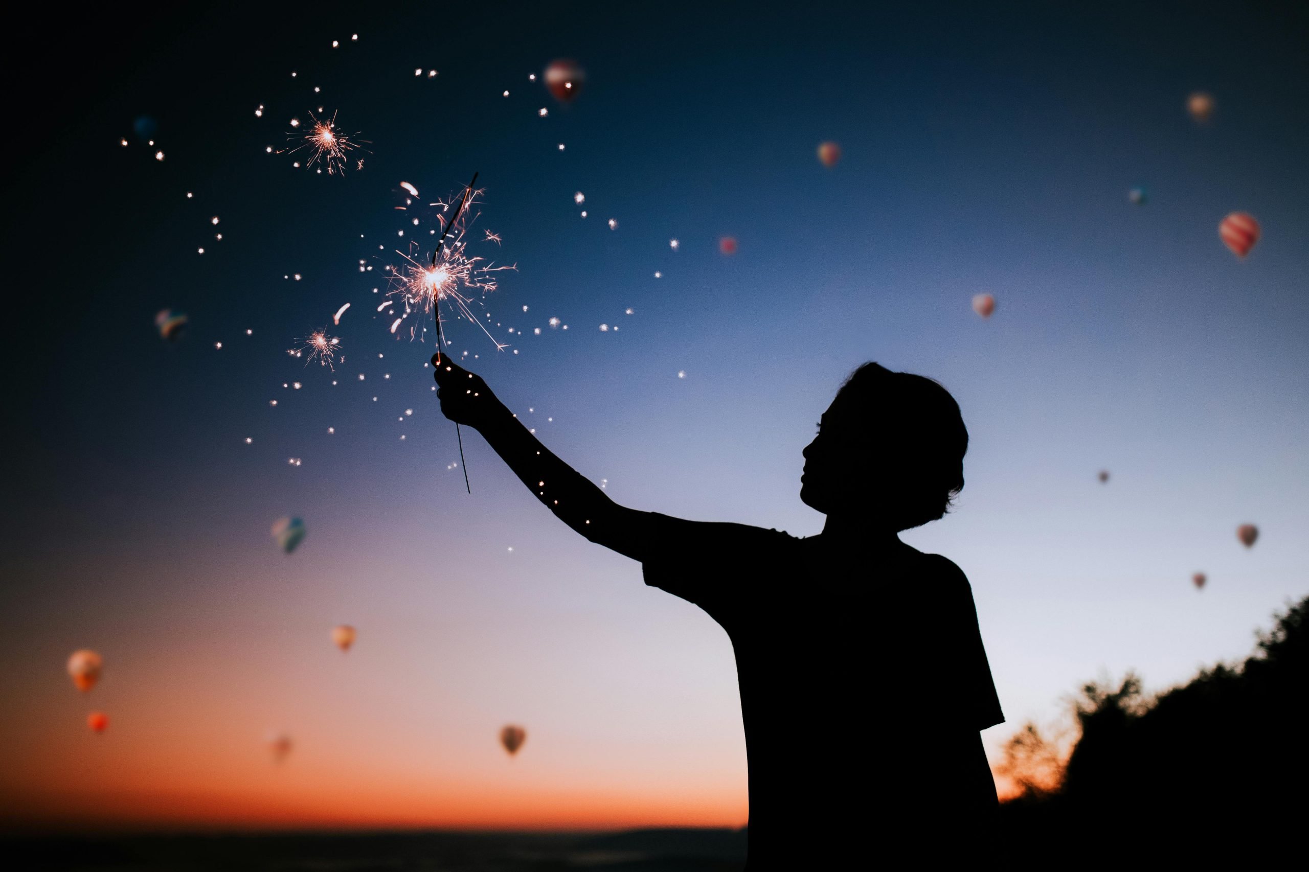 silhouette of young boy lifting his hand to the sky at night