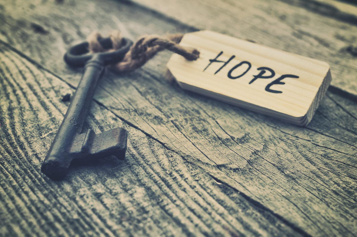 image of an old fashioned key lysing on a table with a tag tied to it which reads hope